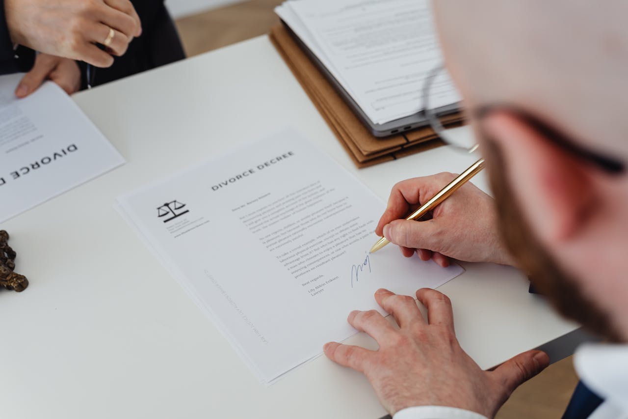 Person signing divorce documents at a desk — T&S Legal divorce solicitors London