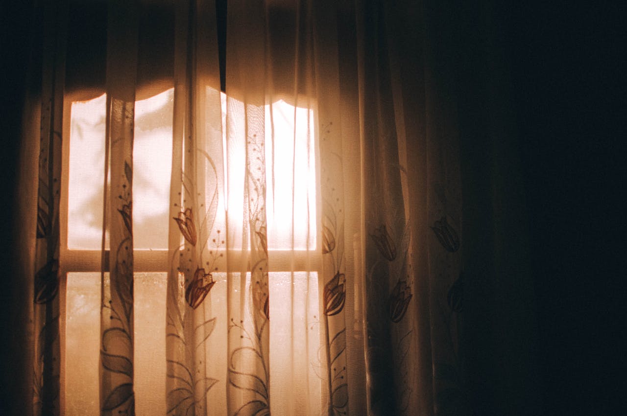 Warm sunlight through window curtains representing hope and safety — domestic abuse legal support