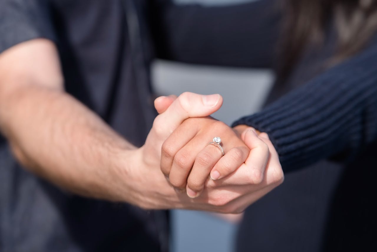 Couple holding hands with engagement ring — prenuptial agreement solicitors London
